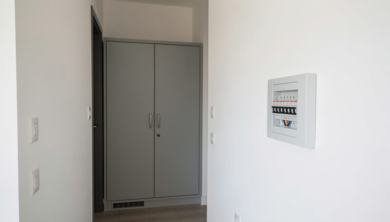 Armario técnico cerrado y cuadro de protecciones en la pared blanca del pasillo de un piso moderno