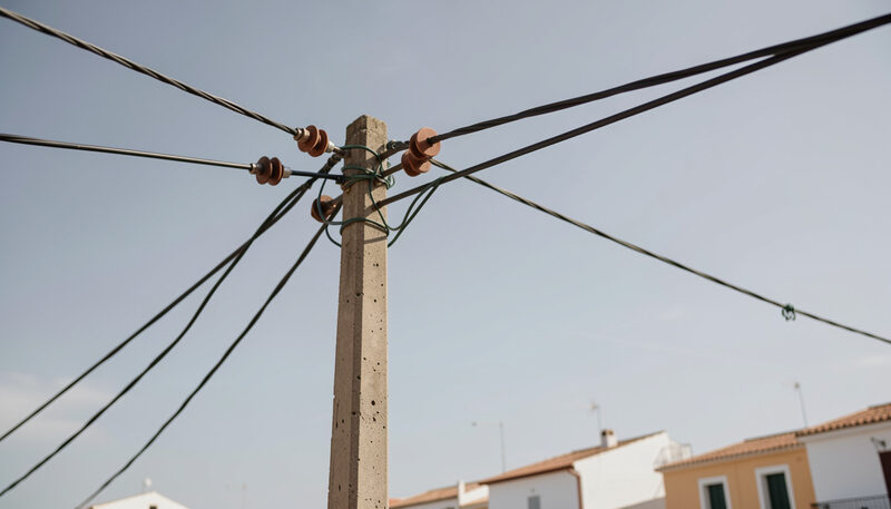 Cables de baja tensión y aisladores de porcelana sobre un poste de hormigón recortado contra el cielo